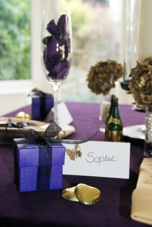 a purple tablecloth, purple petals and purple favor boxes