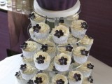 a wedding cake designed as a giant cupcake in neutrals and purple and real cupcakes with purple sugar blooms on top