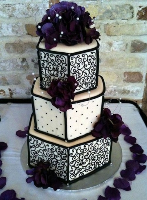 a black and white patterned wedding cake topped with purple flowers