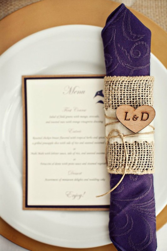 A purple patterned napkin with a burlap napkin ring and a monogrammed heart