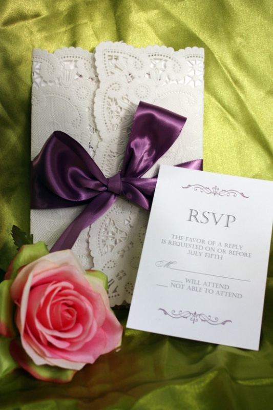 White lace wedding stationery with a silk purple bow