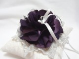 a white lace ring pillow decorated with purple fabric flowers is a stylish way to deliver the rings