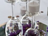 a wedding centerpiece of glasses with candles and with purple blooms inside