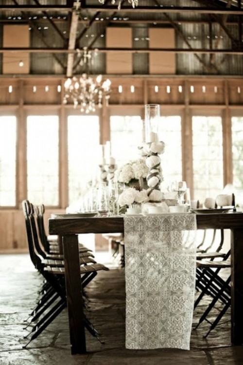 a dark-stained dining table and chairs contrast the white lace runner, candles and white blooms and together they create a perfect symphony