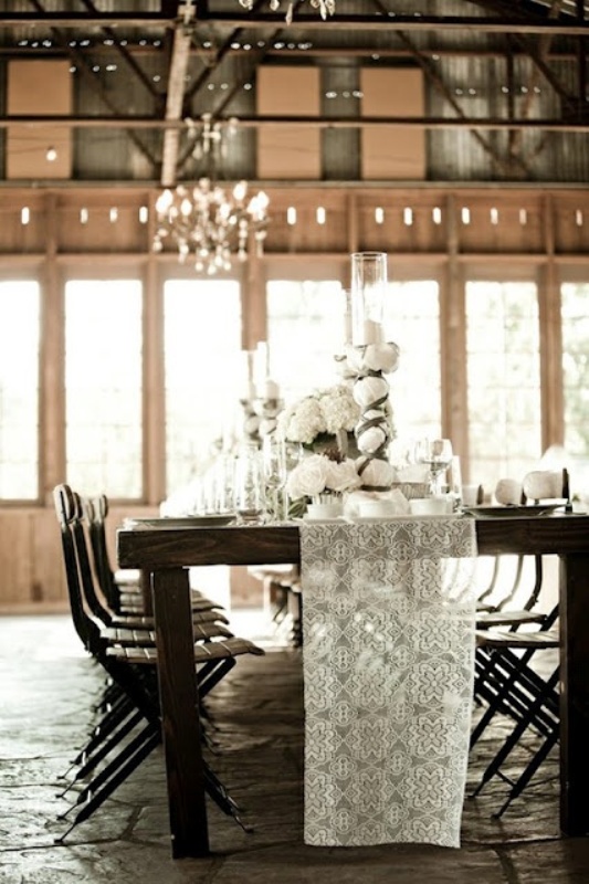 a dark stained dining table and chairs contrast the white lace runner, candles and white blooms and together they create a perfect symphony