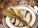 a creative wedding tablescape with a wooden runner, sheer, white and zebra plates, a bold napkin with an embellished napkin ring and a leafy placemat