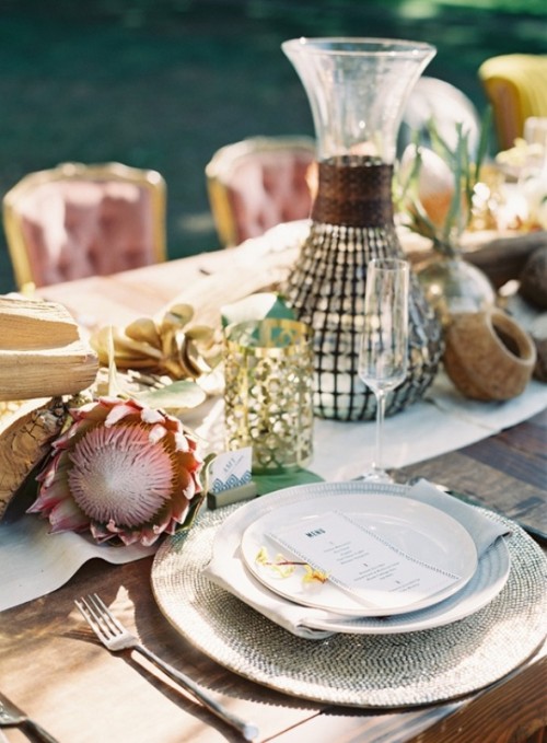 a safari wedding tablescape with king proteas, candles, gold candleholders, woven charger and simple cutlery