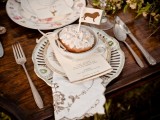 a safari inspired wedding tablescape with vintage chargers and plates, with printed linens, greenery and blooms and a cake in a cup topped with a lion