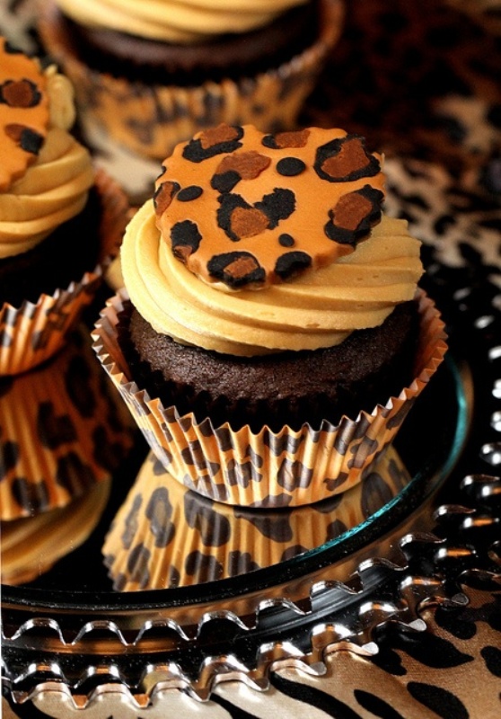 chocolate cupcakes with frosting and a leopard cookie on top is a fun and bold idea of a wedding dessert