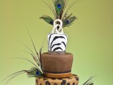 a bright safari wedding cake with a zebra, leopard and brown tier, with peacock feathers and twigs looks unique