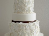 a white wedding cake with two floral tiers and two sleek ones plus brown ribbons looks ethereal