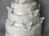 a neutral floral lace wedding cake decorated with sugar butterflies is a very chic and girlish idea