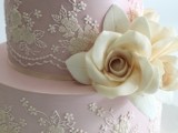 a blush wedding cake with white lace, sugar blooms and a ribbon bow on the bottom is a very cute idea