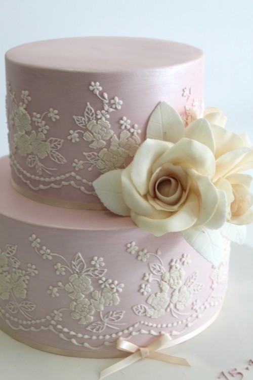 a blush wedding cake with white lace, sugar blooms and a ribbon bow on the bottom is a very cute idea