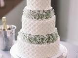 a white lace wedding cake with baby’s breath in between is ideal for a rustic or vintage-inspired wedding