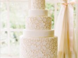 a tan wedding cake decorated with white edible lace and black head silhouettes as toppers for a catchy touch