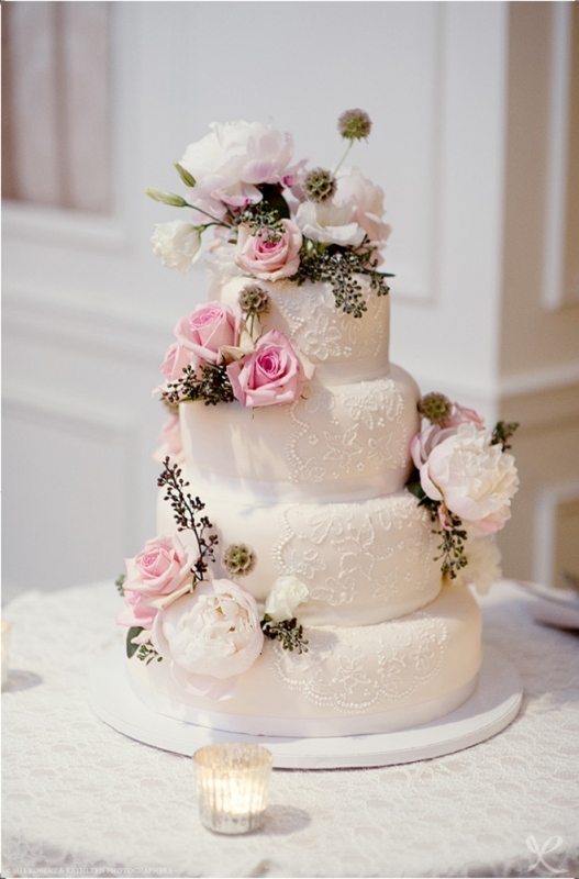 A white lace wedding cake topped with fresh pink and white blooms and greenery looks very catchy and very fresh