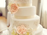 a white wedding cake decorated with tan lace and sugar blooms in pink and white is a cool idea to rock