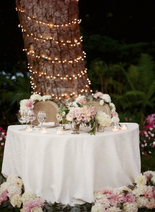 the table is decorated with lush pink and white blooms, the so are the chairs and the same blooms surround the table