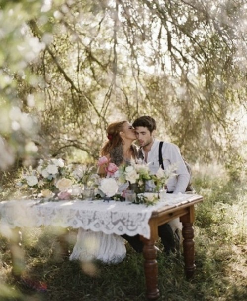 a white lace tablecloth and several arrangements in pink and white create a lush and romantic sweetheart table