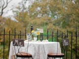 the sweetheart table accented with a white lace tablecloth, pumpkins, blooms and coordinating signage on the chairs