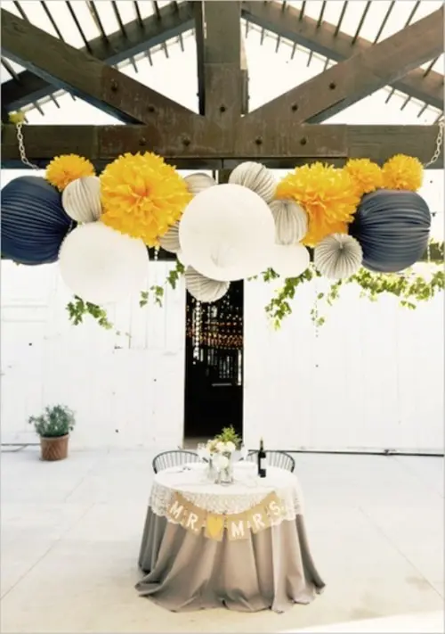 the sweetheart table accented with a burlap bunting and colorful paper balls over the table