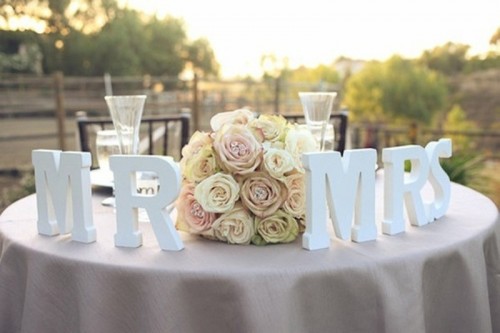 a lush pastel floral centerpiece and letter decor will make your sweetheart table chic and elegant