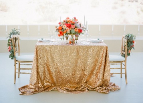 a gold sequin tablecloth, a lush and bold floral centerpiece and chairs decorated with bright blooms and air plants will highlight your space