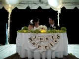 a paper bunting, candles, greenery garlands and a white florla centerpiece to highlight the sweetheart table