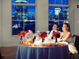 a table runner of bright petals, candles and floral arrangements in sheer vases to accent the sweetheart table