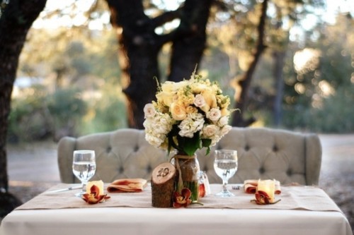a lush floral centerpiece, candles, fall leaves and a rustic table number for an accent