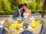 letters, an ampersand, greenery, moss and bright blooms for decorating the sweetheart table in a colorful way