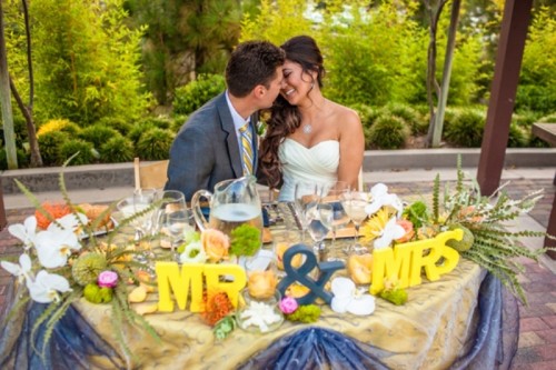 letters, an ampersand, greenery, moss and bright blooms for decorating the sweetheart table in a colorful way
