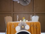 a bright tablecloth, contrasting paper fans, a chalkboard sign and paper fans on the wall behind the table