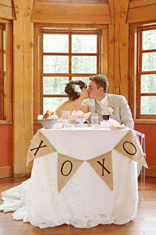 a sweetheart table covered with a lace tablecloth and a burlap bunting for a rustic touch