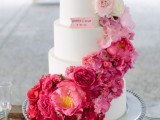 a white buttercream wedding cake decorated with ombre blooms from white to pink and hot red is a bold and catchy solution for a summer wedding