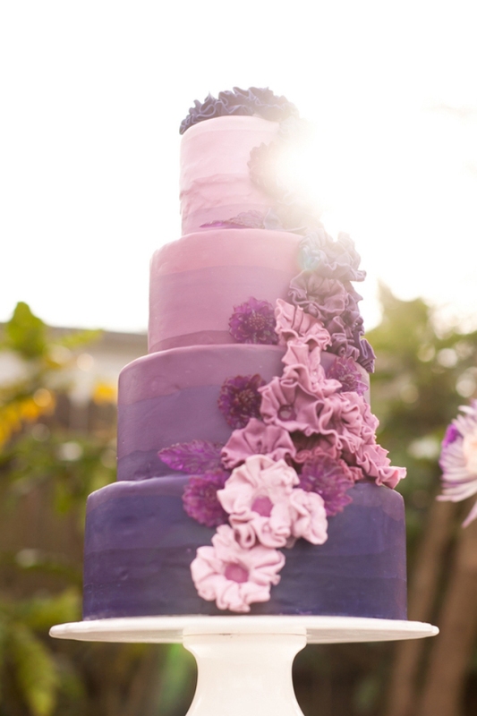 A bright wedding cake with an ombre effect, from light pink to lilac and purple, with lots of matching sugar blooms