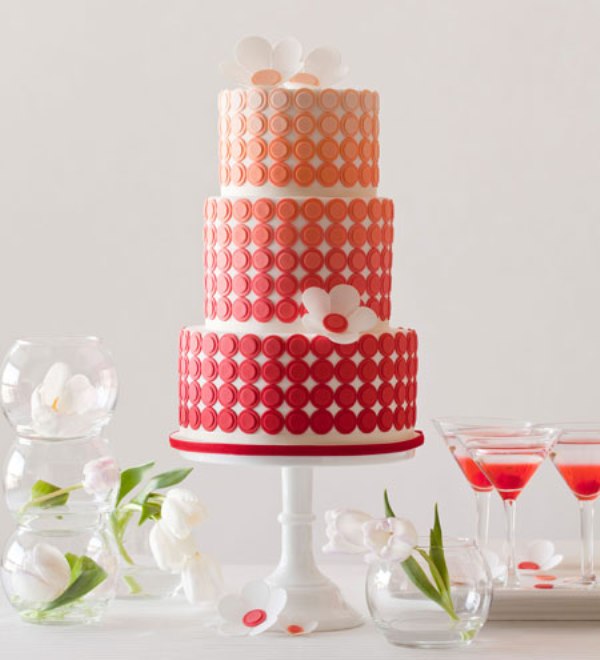 A bright modern wedding cake with an ombre effect, with yellow, orange and red tiers and some sugar blooms is a bold and cool idea for a wedding in summer