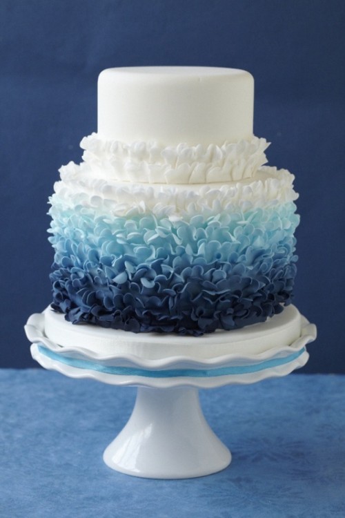 a bold and cool wedding cake with a white and ombre tier, from light blue to navy and ruffles is a lovely idea for a nautical wedding