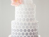 a subtle ombre grey wedding cake with a pink sugar flower is a lovely idea for a spring or summer wedding