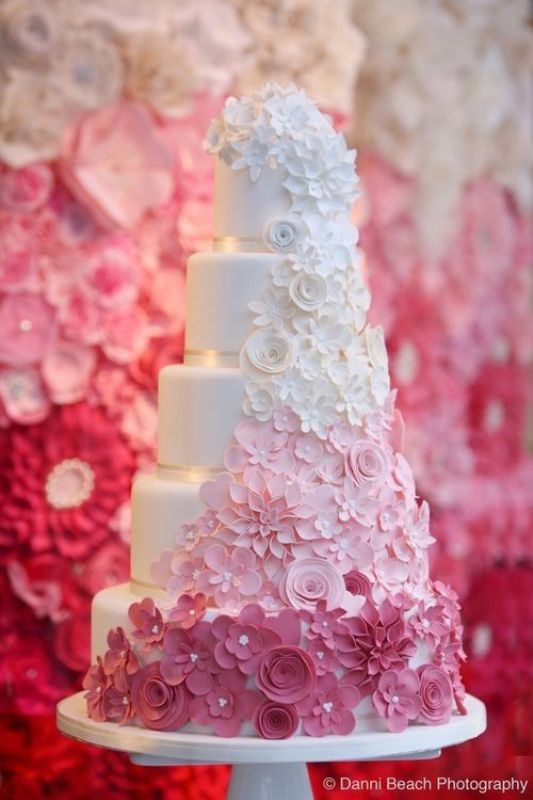 A white buttercream wedding cake with sugar blooms from white to light pink and bolder pink is a cool idea for a spring or summer wedding