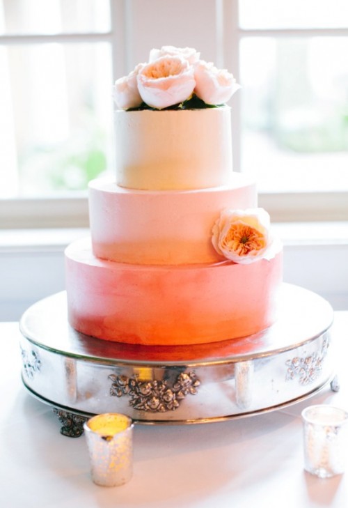 an ombre wedding cake with light pink to orange tiers, with fresh blooms is a very bright and cool idea for a summer or spring wedding