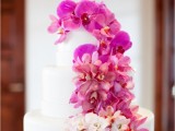 a white buttercream wedding cake with ombre blooms from fuchsia to white is a catchy and bold idea for a colorful wedding