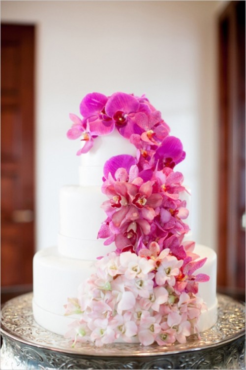 a white buttercream wedding cake with ombre blooms from fuchsia to white is a catchy and bold idea for a colorful wedding