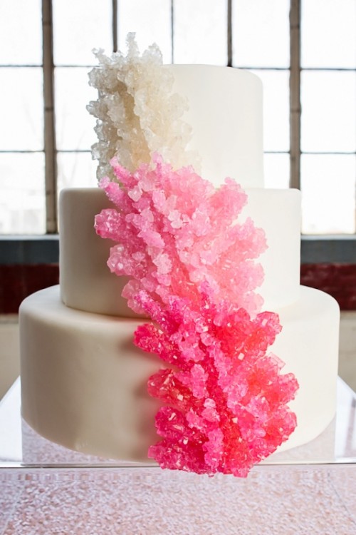 a white buttercream wedding cake with ombre sugar corals - from white to pink and red is a fantastic solution for a beach wedding