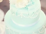 a chic mint green wedding cake with white beading and edible ribbons plus white blooms on top