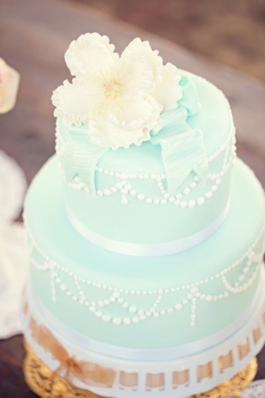 A chic mint green wedding cake with white beading and edible ribbons plus white blooms on top