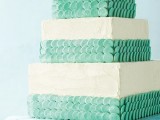 a square textural white wedding cake with mint green scales for decor looks cool, fresh and summer-like