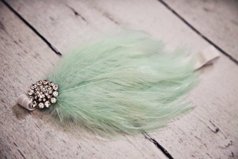 A mint wedding accessory of a feather and a vintage brooch is a cool and cute idea