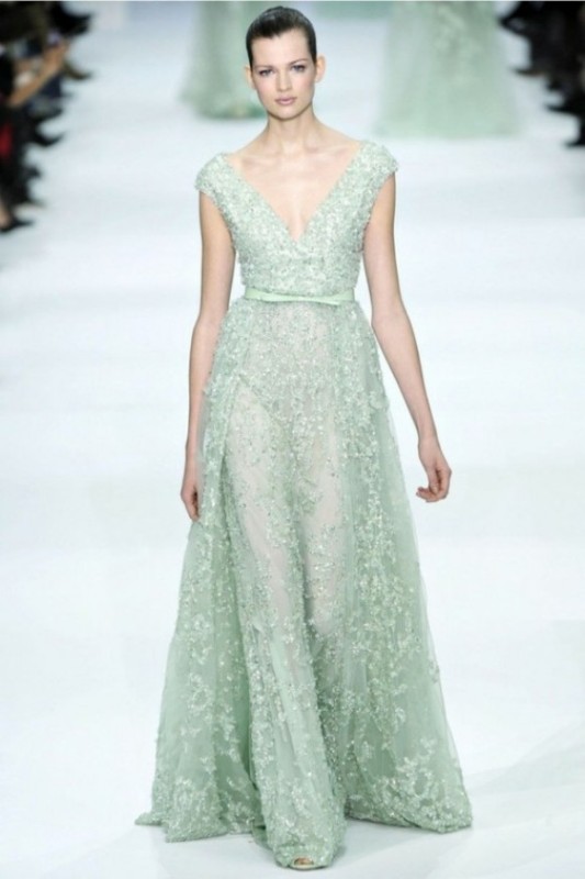 A fully embellished mint colored A line wedding dress with a deep neckline and cap sleeves